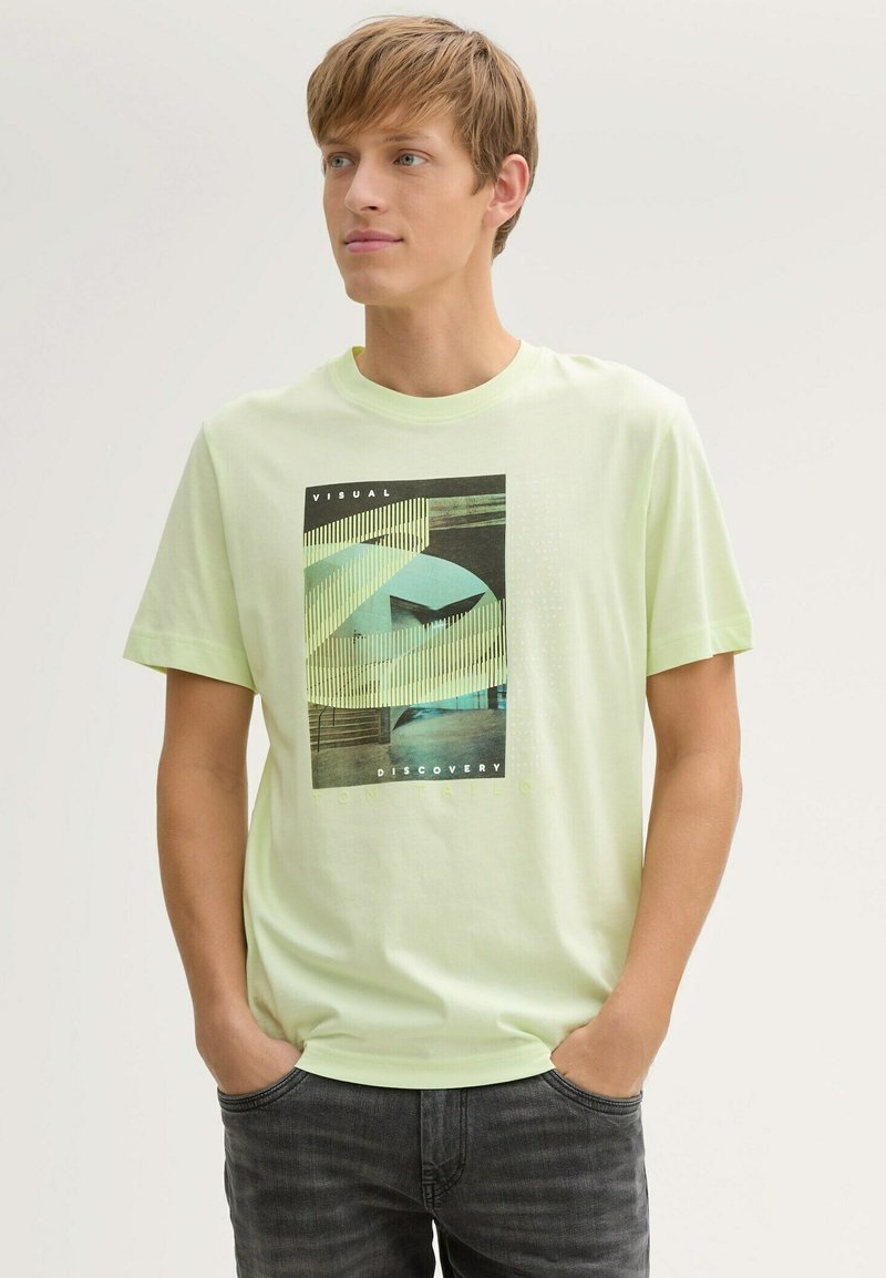 Lichtgroen T-shirt met korte mouwen en een grafische print van abstracte vormen en tekst. Gemaakt van zachte stof, met een relaxte pasvorm en een ronde hals.