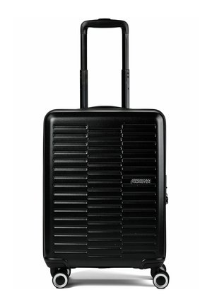 Maleta de mano negra con carcasa dura, estrías horizontales, asa retráctil, cuatro ruedas giratorias y logo de American Tourister en la parte frontal.
