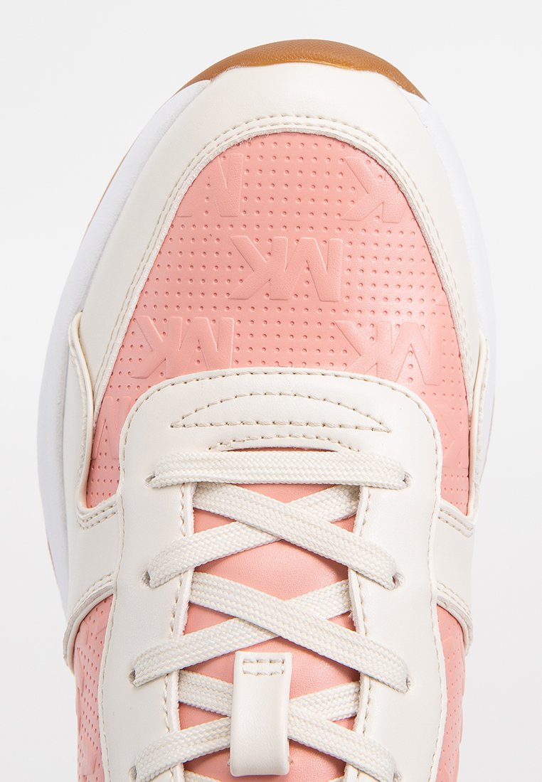 Baskets roses avec des accents en cuir blanc, surface rose texturée arborant un motif de logo, et lacets de couleur claire. Semelle en caoutchouc arrondie.