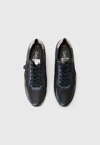 Chaussures en cuir bleu marine avec un bout texturé noir, des accents métalliques argentés au talon et des lacets foncés. Dotées d'une fermeture éclair sur le côté pour un enfilage facile.