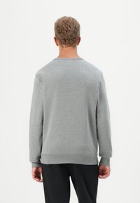 Sudadera gris heather con mangas largas, cuello redondo y puños acanalados. La parte trasera es lisa, con un corte estándar y sin diseños.