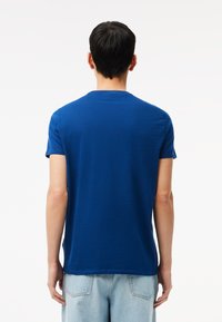 T-shirt blu con scollatura a girocollo e maniche corte, realizzato in morbido tessuto, mostrato da dietro, caratterizzato da un design semplice e una vestibilità comoda.