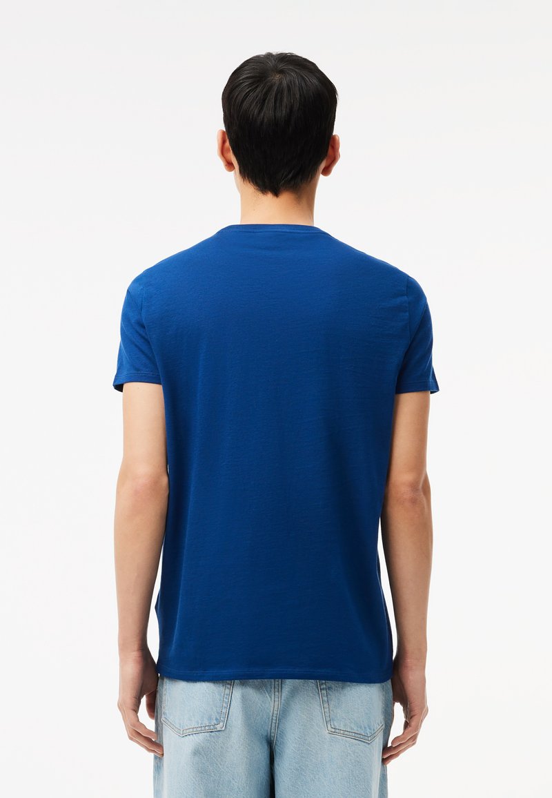 Blaues Rundhals-T-Shirt mit kurzen Ärmeln, aus weichem Stoff, von hinten betrachtet, mit einem schlichten Design und einer lässigen Passform.