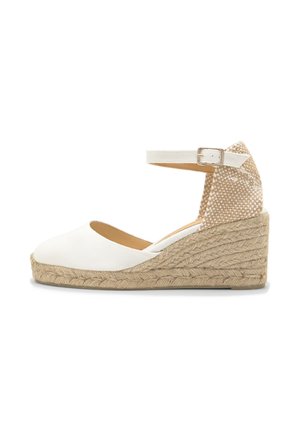 Witte espadrille met wigvormige zool, enkelbandje met gesp, gevlochten juten plateauzool en beige textuur aan de hielkap.