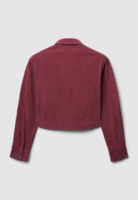 Camicia corta in velluto a coste bordeaux con maniche lunghe, colletto classico e polsini con bottoni. Tessuto strutturato con coste verticali.