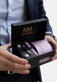 Lila Krawatte in einer schwarzen Box, bestehend aus einer strukturierten Krawatte, silbernen Manschettenknöpfen und einer Krawattennadel. Box mit goldenem Logo "MASSI MORINO" verziert.