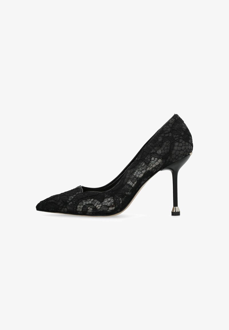 Chaussure à talon haut en dentelle noire à bout pointu avec un talon stiletto fin, comportant un petit accent métallique à la base.