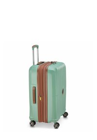 Valise rigide vert menthe avec des accents marron, coins arrondis, double zip, et quatre roues pivotantes pour la mobilité.