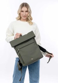 Sac à dos à rabat en vert olive, fabriqué à partir d'un matériau lisse et durable. Doté d'une poche zippée à l'avant et de bretelles réglables. Design minimaliste.