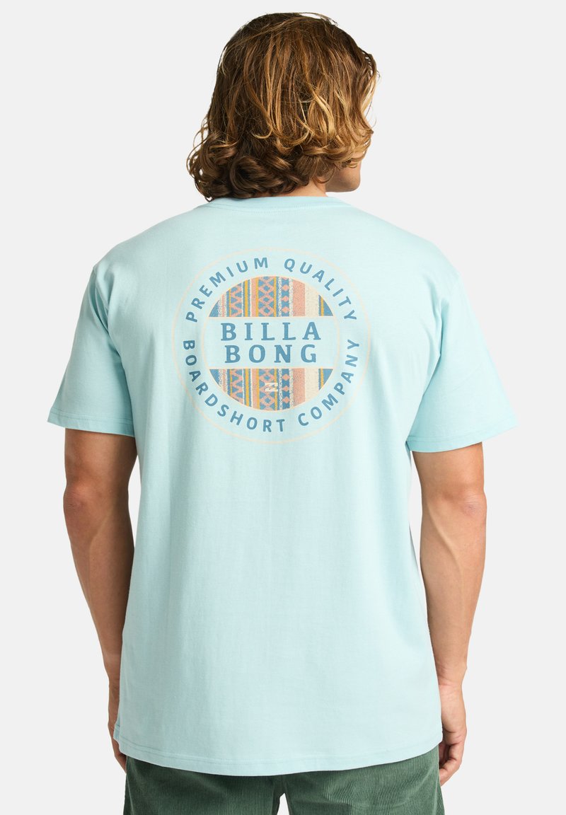 T-shirt azzurro chiaro con una grafica circolare sul retro che riporta il testo "BILLA BONG" e motivi multicolori, realizzata in cotone.