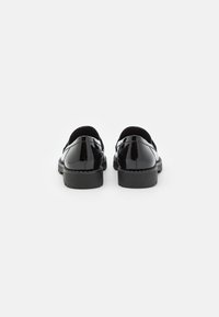 Schwarze Lacklederschuhe mit glatter Oberfläche, abgerundeter Zehe, niedrigem Absatz und minimalistischem Design. Die Rückseite weist einen eleganten, nahtlosen Schnitt auf.
