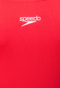 Maillot de bain rouge en tissu lisse avec un design ajusté. Présente le logo "Speedo" blanc dans la zone supérieure de la poitrine.