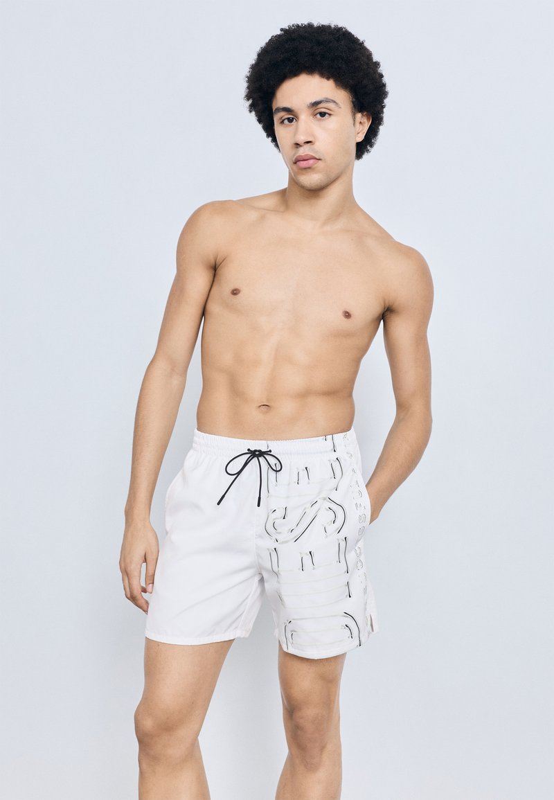 Witte zwemshorts met een trekkoord in de taille, met een gestructureerd patroon aan één zijde en een gladde afwerking aan de andere.