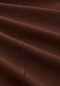 Tissu marron avec une texture lisse, présentant de douces ondulations et une subtile texture, adapté pour le revêtement ou les vêtements.