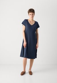 Navy blue short-sleeve dress with a V-neck and a loose fit. Made from soft fabric, it falls just above the knees with a simple design.