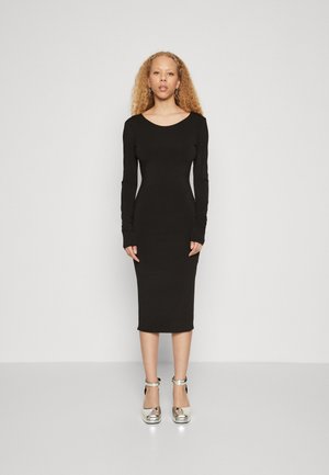 Svart langermet bodycon-kjole med scoop-hals, midt på leggen, glatt tekstur, brukt med sølvfargede blokkheled sko.
