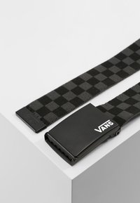 Zwart en grijs geblokte geweven riem met een zwarte metalen gesp waarop het Vans-logo staat. De stof heeft een soepele textuur.