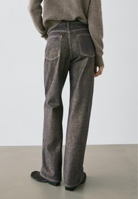 Jean en denim bleu foncé, coupe jambes larges, finition légèrement usée. Comprend des poches arrière classiques et des détails subtils de couture.