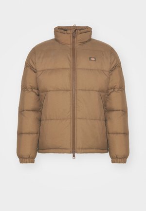 Brązowa kurtka puchowa z wysokim kołnierzem, zapinana na zamek, z elastycznymi mankietami. Ma poziome pikowane sekcje oraz małe logo na klatce piersiowej.