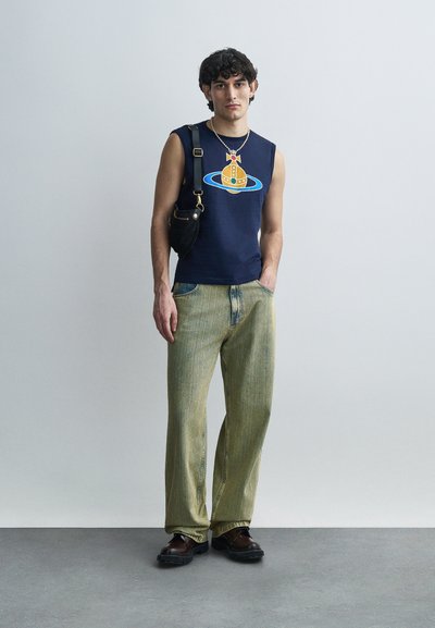 Ναυτικό αμάνικο μπλουζάκι με γραφικό σχέδιο, φαρδύ παντελόνι με ανοιχτό πράσινο ριγέ, μαύρη τσάντα χιαστί και καφέ χοντρά παπούτσια.