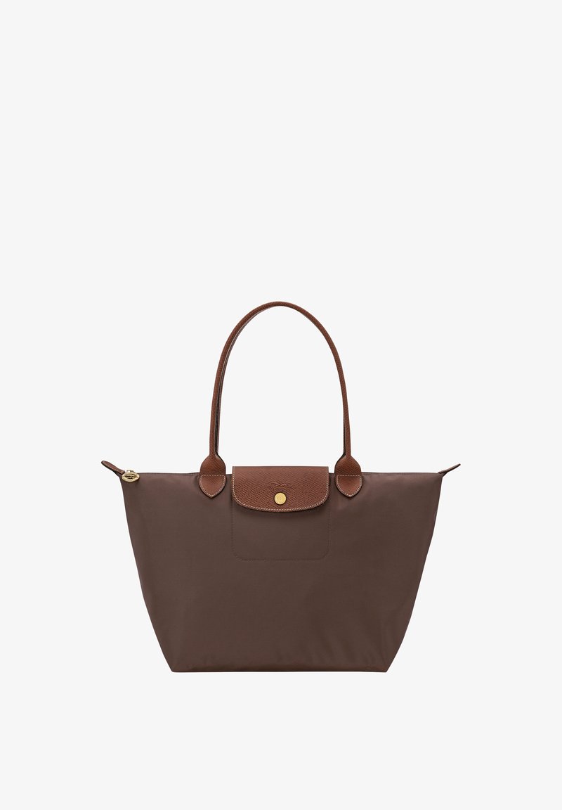 Brown tote bag with long handles, a front flap with a gold button, and a zipper closure on top against a white background.