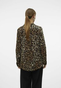 Košile s leopardím potiskem vyrobená z lehkého materiálu, s dlouhými rukávy, zapínáním na knoflíky a zaobleným lemem. Zobrazený pohled zezadu.