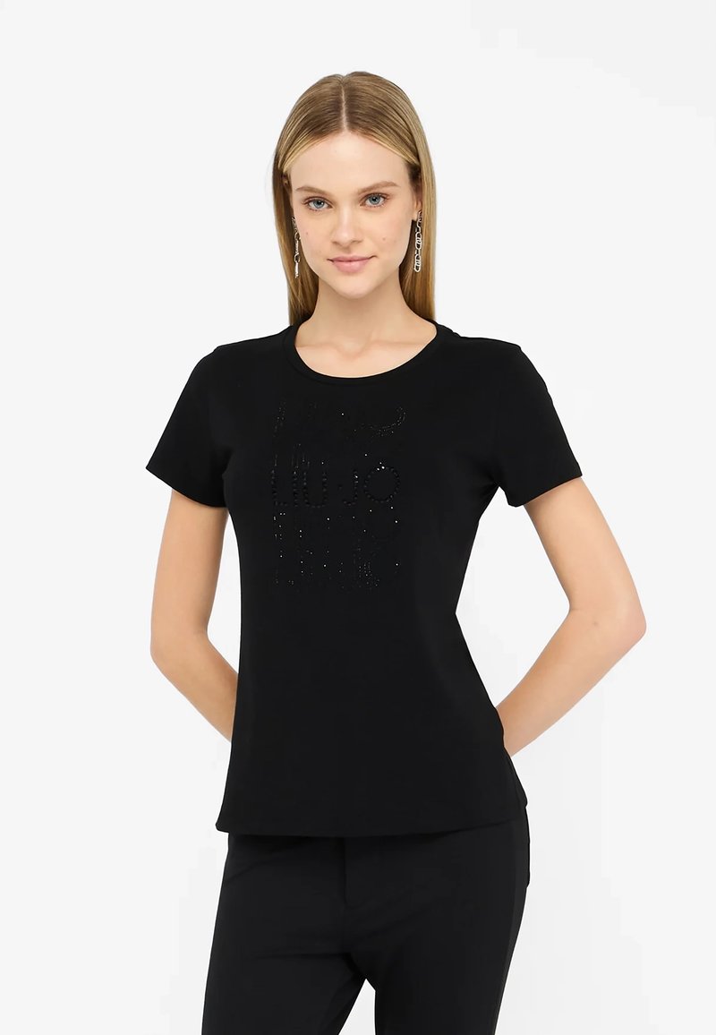 T-shirt nera a maniche corte con colletto rotondo, con un design del logo in strass tono su tono sul fronte. Tessuto liscio e fit su misura.