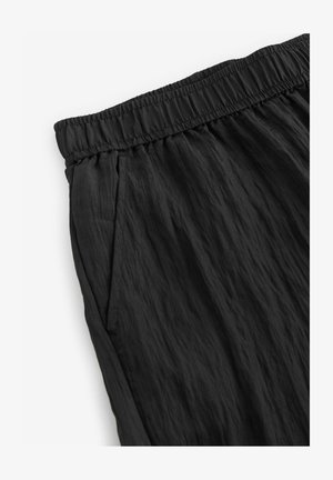 Mustad, kerge kangast püksid musta värviga, millel on elastne vöökoht, tekstuuritud pind ja küljetaskud.