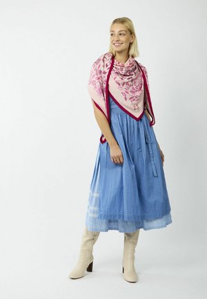 Blau gestreiftes Kleid mit Stickerei, kombiniert mit einem rosa Blumenschal mit rotem Saum. Das Model trägt cremefarbene Blockabsatzstiefel.
