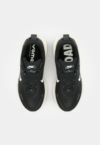 Schwarze Sportschuhe mit einem gewebten Obermaterial, weißen Akzenten und einer gepolsterten cremefarbenen Sohle. Verfügt über Schnürsenkel, eine Schlaufe zum Anziehen und bedruckte Markenlogos im Inneren.