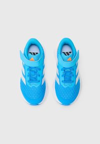 Par de zapatillas deportivas de color azul brillante con rayas laterales blancas, detalles de logotipo en naranja y correas de velcro sobre un fondo blanco.