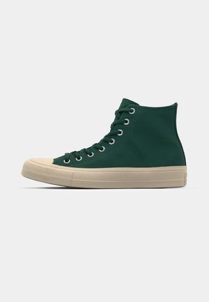 Groene hoge sneaker met een bovenkant van canvas, beige rubberen zool en metalen veterogen. Heeft een ronde neus en veters aan de voorkant.