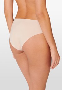 Beige saumattomat alusvaatteet, joissa on sileä pinta, keskipitkä vyötärödesign ja täysi peittävyys takana, tyylikäs ja yksinkertainen leikkaus.