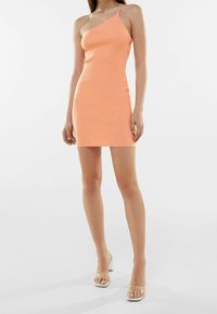 Robe côtelée à une épaule en corail doux, silhouette ajustée, longueur aux genoux. Caractérisée par une texture lisse et un design minimaliste.