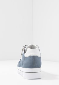 Baskets en daim bleu avec accents blancs, présentant une surface texturée et un design perforé. Semelle blanche épaisse avec relief antidérapant.