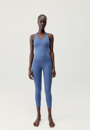Blauwe sportset bestaande uit een mouwloos top met een V-hals en een midi-hoge legging. Soepele, rekbare stof met een matte afwerking.