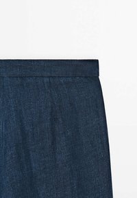 Jupe en denim bleu foncé avec une taille droite, texture lisse, sans poches visibles ni ornements.