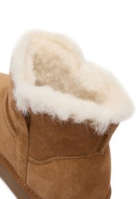 Botine din suede maro cu căptușeală pufoasă din blană crem, guler rotunjit și detalii de cusătură întărită pe lateral.