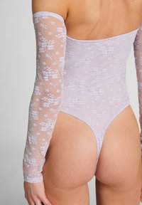 Lila kant bodysuit met lange doorzichtige mouwen, bloemenpatroon, hoge beenopeningen en een lage rug, die een aansluitend ontwerp benadrukt.