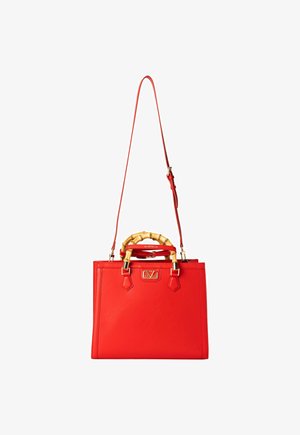 Red leather handbag with a structured shape, bamboo handle, detachable shoulder strap, gold hardware, and embossed logo on the front.