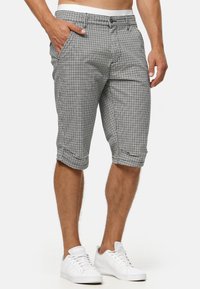 Schwarz-weiße karierten Shorts mit umgeschlagenen Säumen, ausgestattet mit Seitentaschen und einem Knopfverschluss. Hergestellt aus leichtem Stoff, lässiger Schnitt.