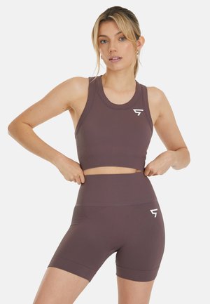 Set di activewear marrone a coste composto da un reggiseno sportivo corto e pantaloni corti a vita alta, caratterizzati da una texture liscia e un accento con logo sul fianco sinistro.