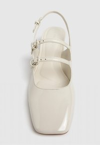 Chaussure femme en cuir laqué crème, type slingback, avec bout carré et deux sangles à boucle réglables sur le dessus.
