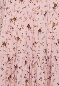 Tecido estampado com flores em rosa suave, com pequenas flores multicoloridas. Apresenta camadas com babados e um material leve e texturizado.