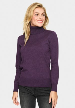 Lila Rollkragenpullover aus weichem Strickmaterial mit langen Ärmeln und geripptem Saum, kombiniert mit dunklen Jeans.