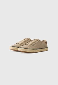 Brune stoff sneakers med rund tå, espadrille-inspirert jute såle, og brune skinnaksenter på hælen og snorene.