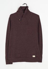 Bordeauxfärgad tröja med krage, iögonfallande med en knapp, framfickor och en etikett på fållen. Mjuk, strukturerad tyg.