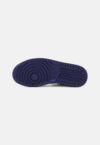 Semelle de basket en caoutchouc violet avec des motifs de bande de roulement circulaires et horizontaux ; présente un logo Nike bien visible près du talon. Texture antidérapante.