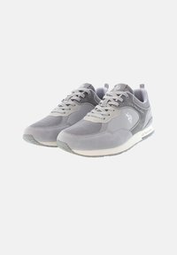 Scarpe sportive grigie con tomaia in mesh e suede, lacci tondi, dettagli riflettenti e suola in gomma testurizzata. Logo del marchio visibile.