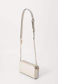 Jasnobeżowa torba typu crossbody o gładkim wykończeniu ze skóry, z łańcuszkiem i regulowanym paskiem, z podwójnymi kieszeniami na zamek i minimalistycznym designem.